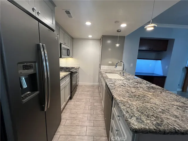 a large kitchen with kitchen island a counter top space a sink stainless steel appliances and cabinets