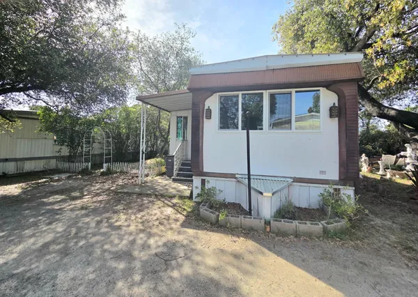 a view of a white house with large trees and outdoor space