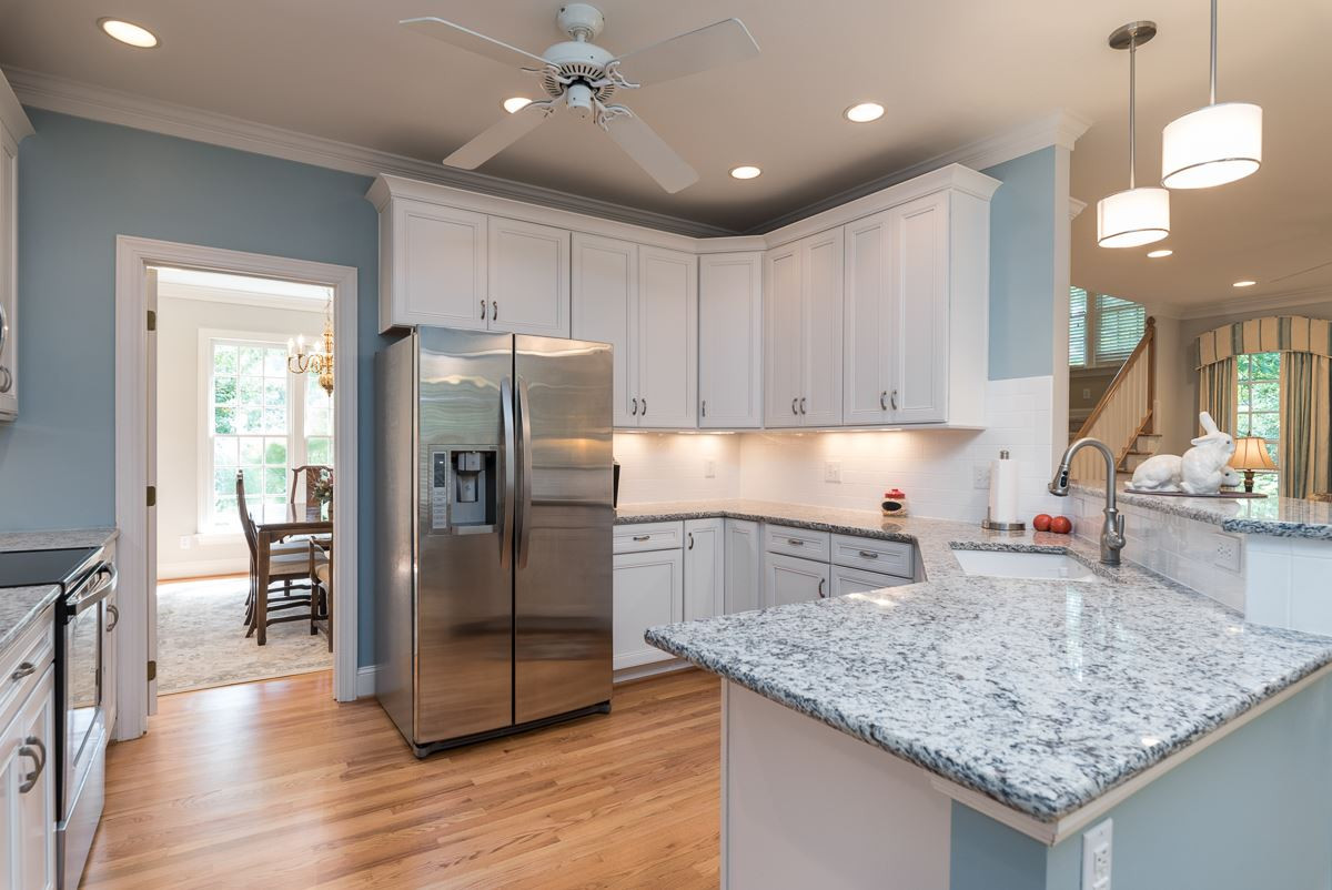 1905 Russell Drive Raleigh, NC 27612 - Photo 9 of 30 Kitchen with new white cabinets, granite tops, subway tile backsplash, under counter lighting, sink & sink faucet, pendant lights, new microwave, SS Bosch dishwasher, Range/Oven and refinished hardwood floors. Kitchen