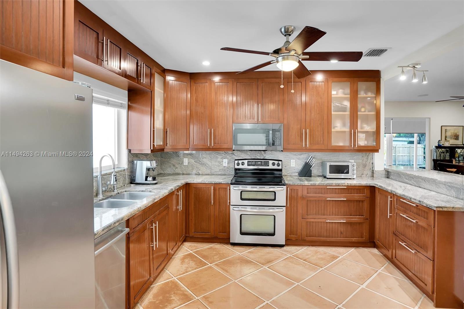 4331 Alton Road Miami Beach, FL 33140 - Photo 6 of 33 a kitchen with stainless steel appliances granite countertop a sink a stove top oven a chimney a counter space and cabinets