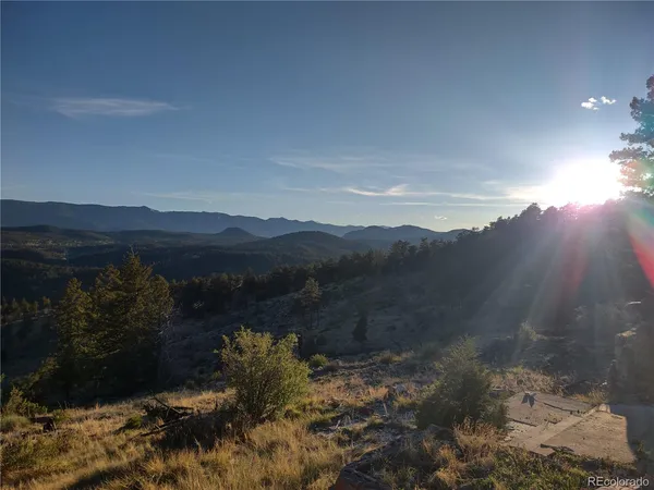 a view of mountain with sunset in background