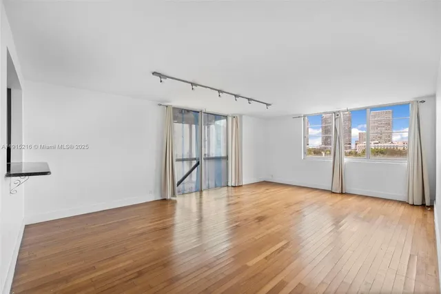 a view of an empty room with wooden floor and a window