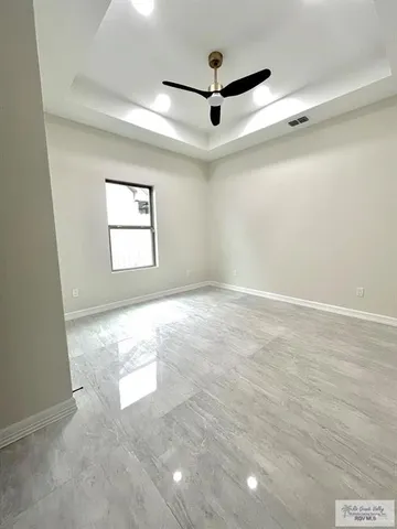 an empty room with windows and ceiling fan