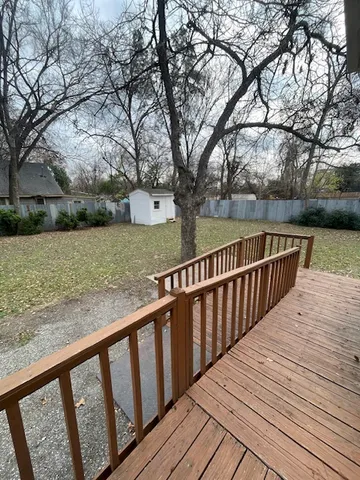 a view of wooden deck and lake with trees in the background