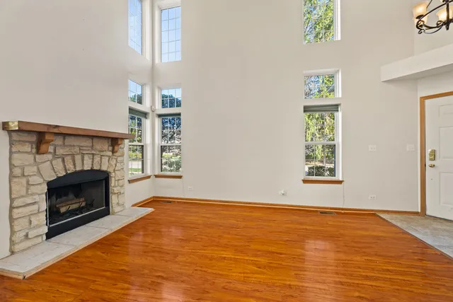 a view of an empty room with wooden floor fireplace and a window