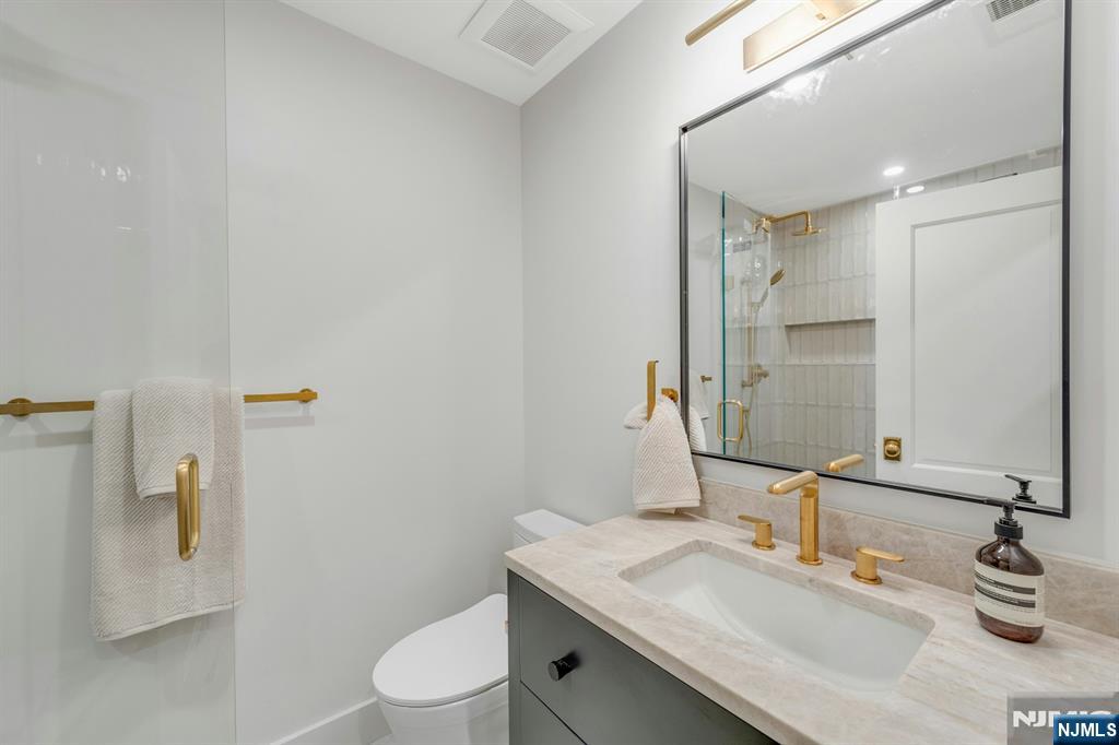 84 Watchung Avenue Montclair, NJ 07043 - Photo 39 of 48 a bathroom with a granite countertop sink a toilet and a mirror