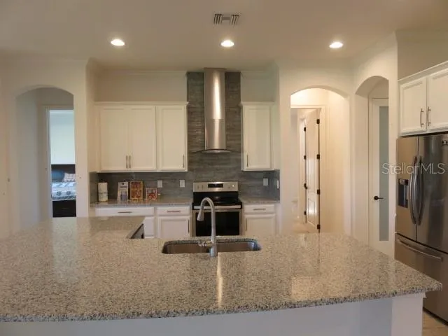 a kitchen with stainless steel appliances granite countertop a refrigerator a stove and a sink