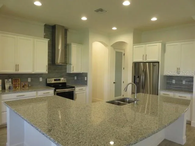 a kitchen with stainless steel appliances granite countertop a sink a stove and a refrigerator