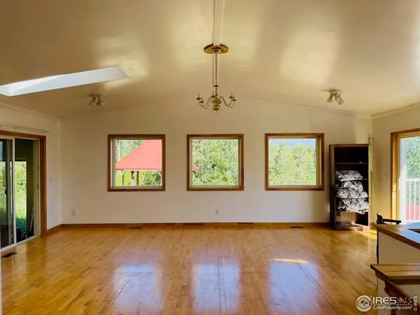 a view of an empty room with window and wooden floor