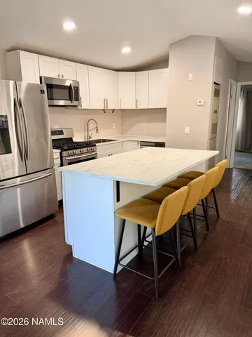 a kitchen with stainless steel appliances granite countertop a refrigerator a stove a sink a microwave and island with wooden floor