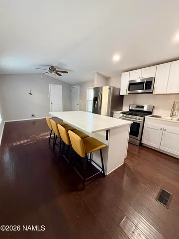 a living room with stainless steel appliances kitchen island granite countertop a stove a sink a refrigerator and a microwave