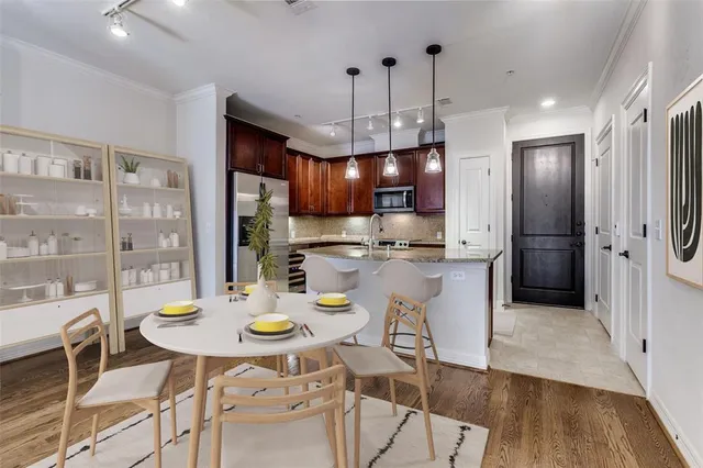 a kitchen with stainless steel appliances granite countertop a dining table chairs and refrigerator