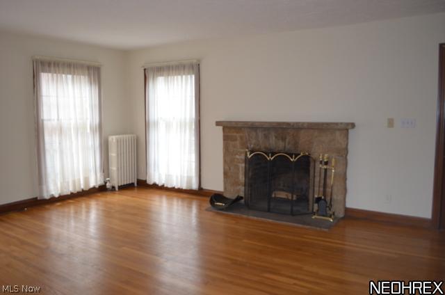 Living room with wood floors, fireplace and floor to ceiling windows.