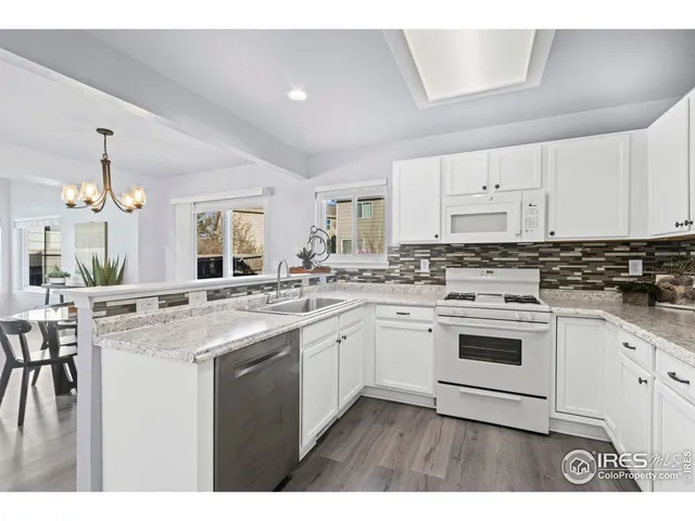 a kitchen with stainless steel appliances granite countertop a stove top oven a sink a dining table and chairs