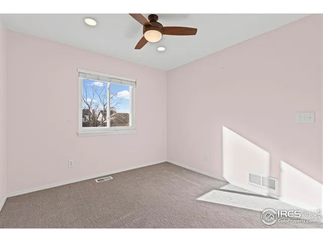 an empty room with wooden floor ceiling fan and window
