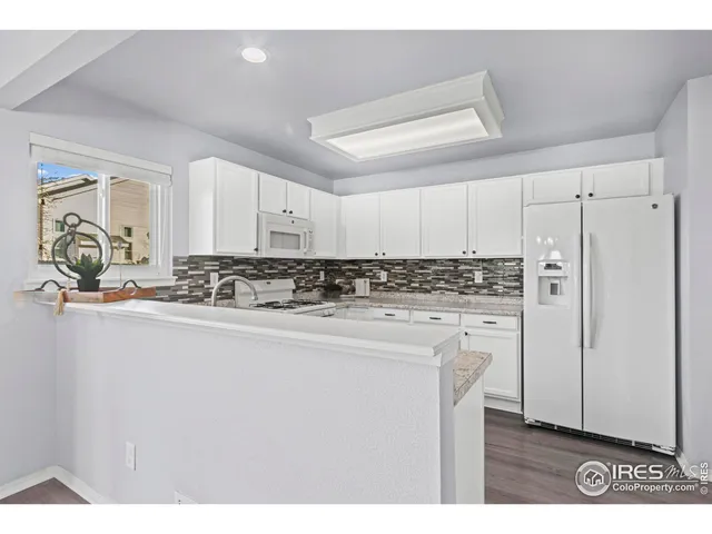 a kitchen with stainless steel appliances granite countertop a refrigerator sink and white cabinets