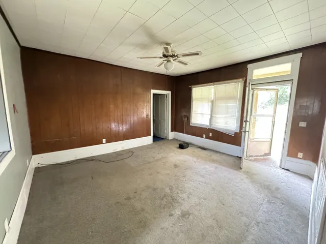an empty room with windows and fan