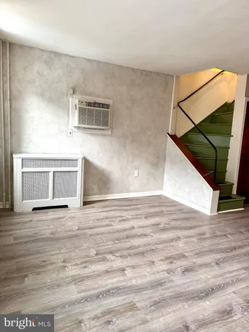a view of a livingroom with wooden floor and staircase