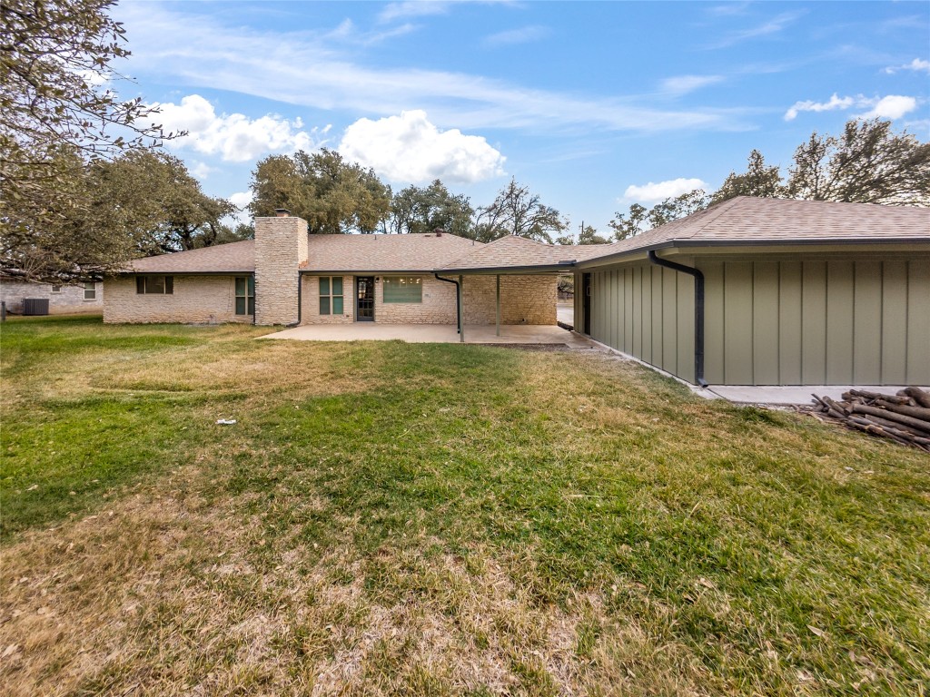 224 Clear Springs Road Georgetown, TX 78628 - Photo 30 of 32 Rear view of house featuring board and batten siding, a yard, a patio area, and a chimney