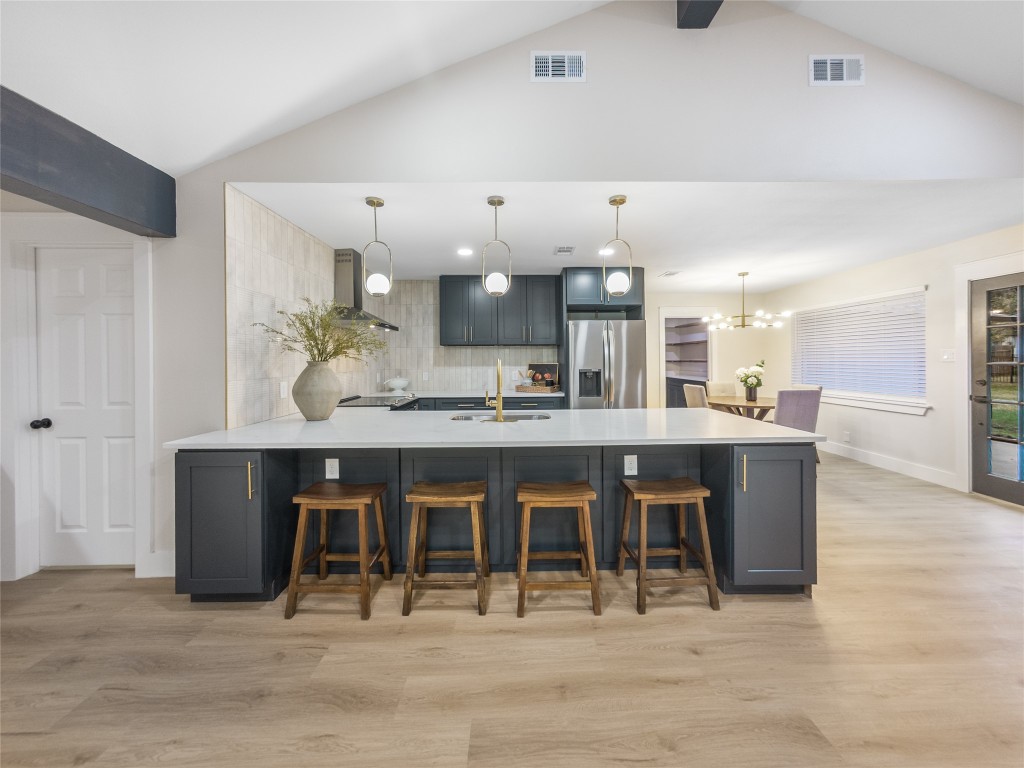 224 Clear Springs Road Georgetown, TX 78628 - Photo 10 of 32 Kitchen with a peninsula, a kitchen breakfast bar, light wood-style flooring, stainless steel refrigerator with ice dispenser, and hanging light fixtures