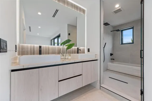 a bathroom with a double vanity sink a mirror and shower