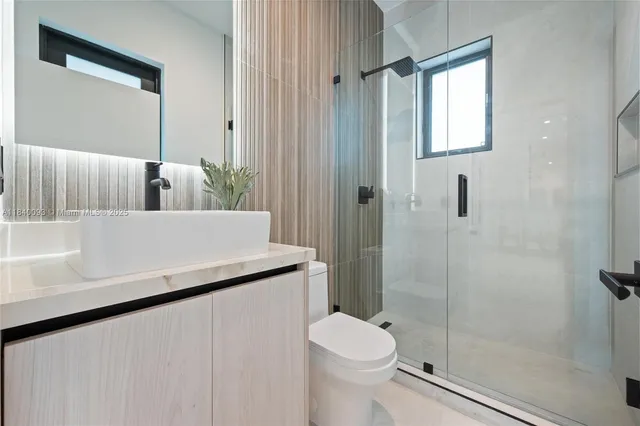 a bathroom with a granite countertop sink toilet and shower