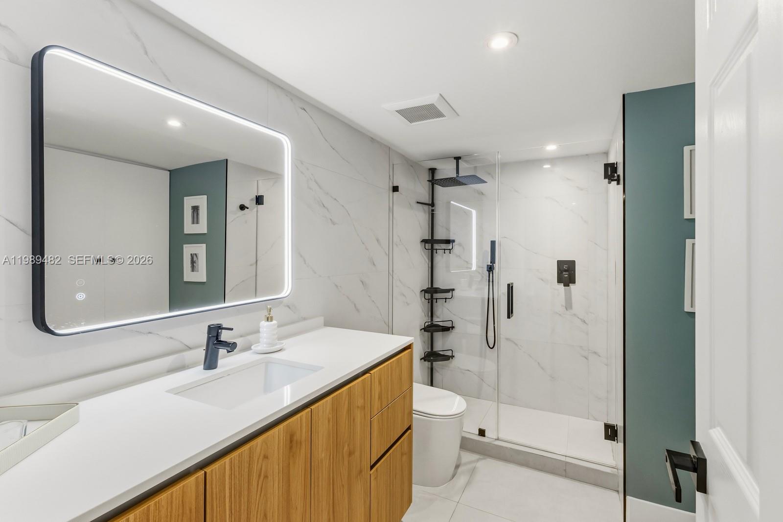 151 Crandon Boulevard, Unit 1222 Key Biscayne, FL 33149 - Photo 21 of 31 a bathroom with a double vanity sink toilet mirror and shower