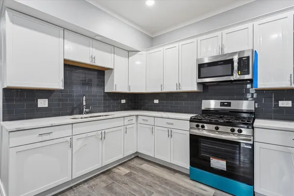 a kitchen with stainless steel appliances granite countertop grey cabinets a stove a sink and dishwasher