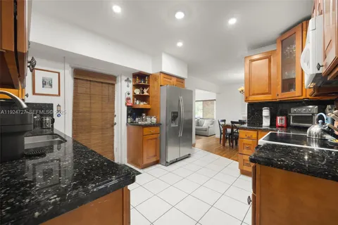 a kitchen with stainless steel appliances granite countertop a refrigerator a stove and a sink with wooden cabinets