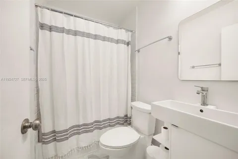 a bathroom with a sink a toilet and shower curtain
