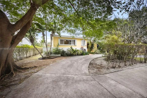 a view of a house with a yard and large tree