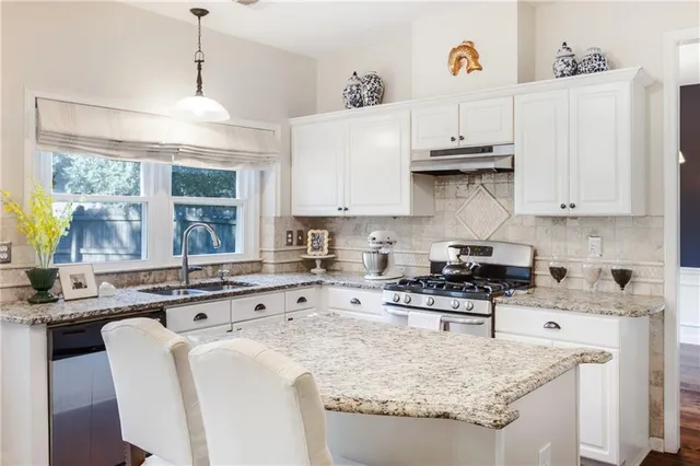 a kitchen with stainless steel appliances white cabinets and wooden floor