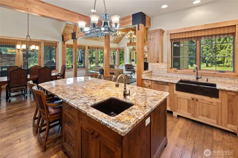 a kitchen with a stove a sink dishwasher and a dining table with garden view