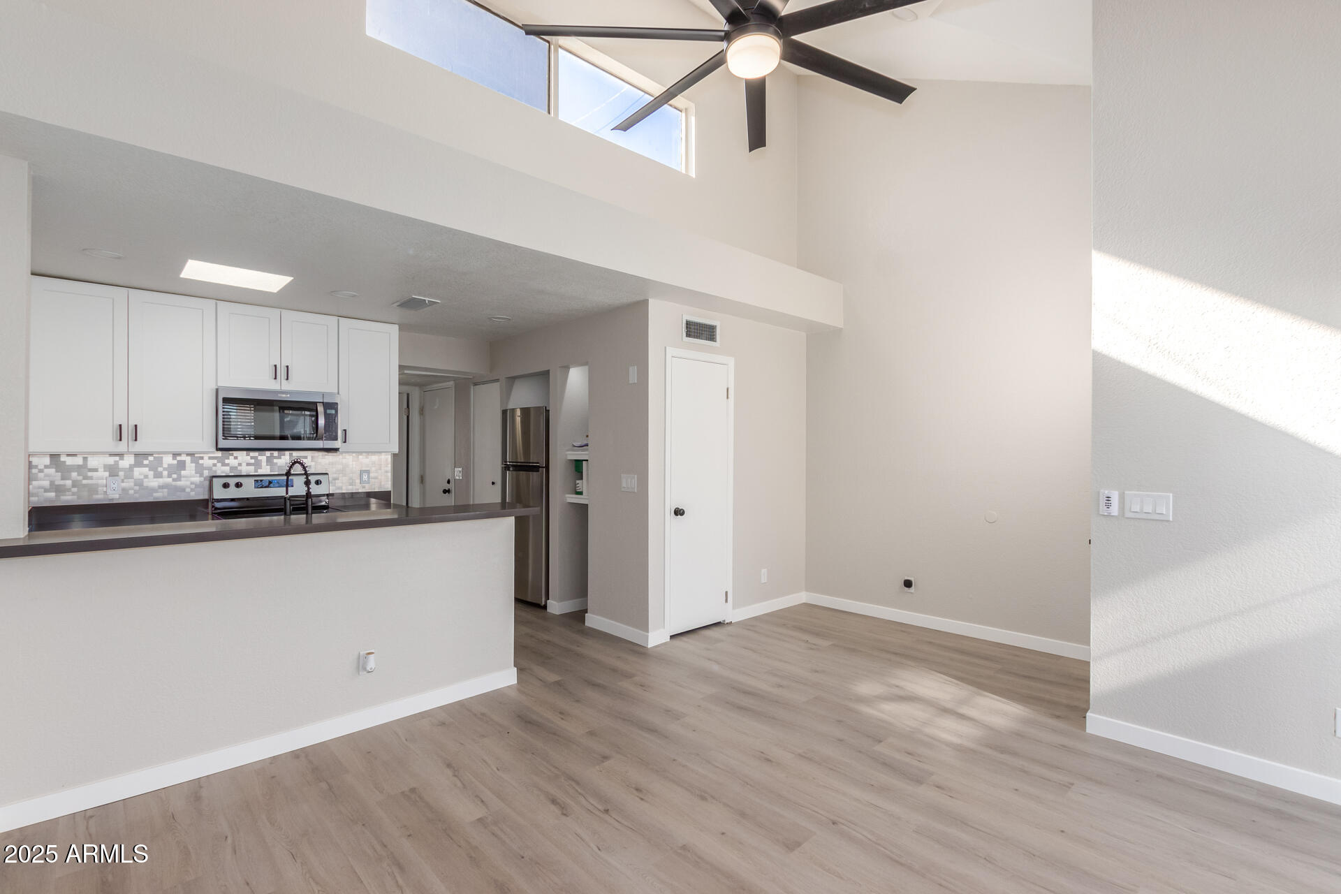 a kitchen with granite countertop a refrigerator a sink and white cabinets