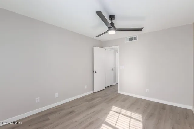 an empty room with wooden floor fan and windows