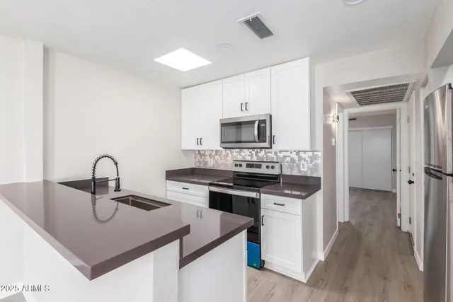 a kitchen with granite countertop a sink cabinets and stainless steel appliances