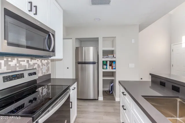 a kitchen with stainless steel appliances granite countertop a refrigerator stove top oven and sink