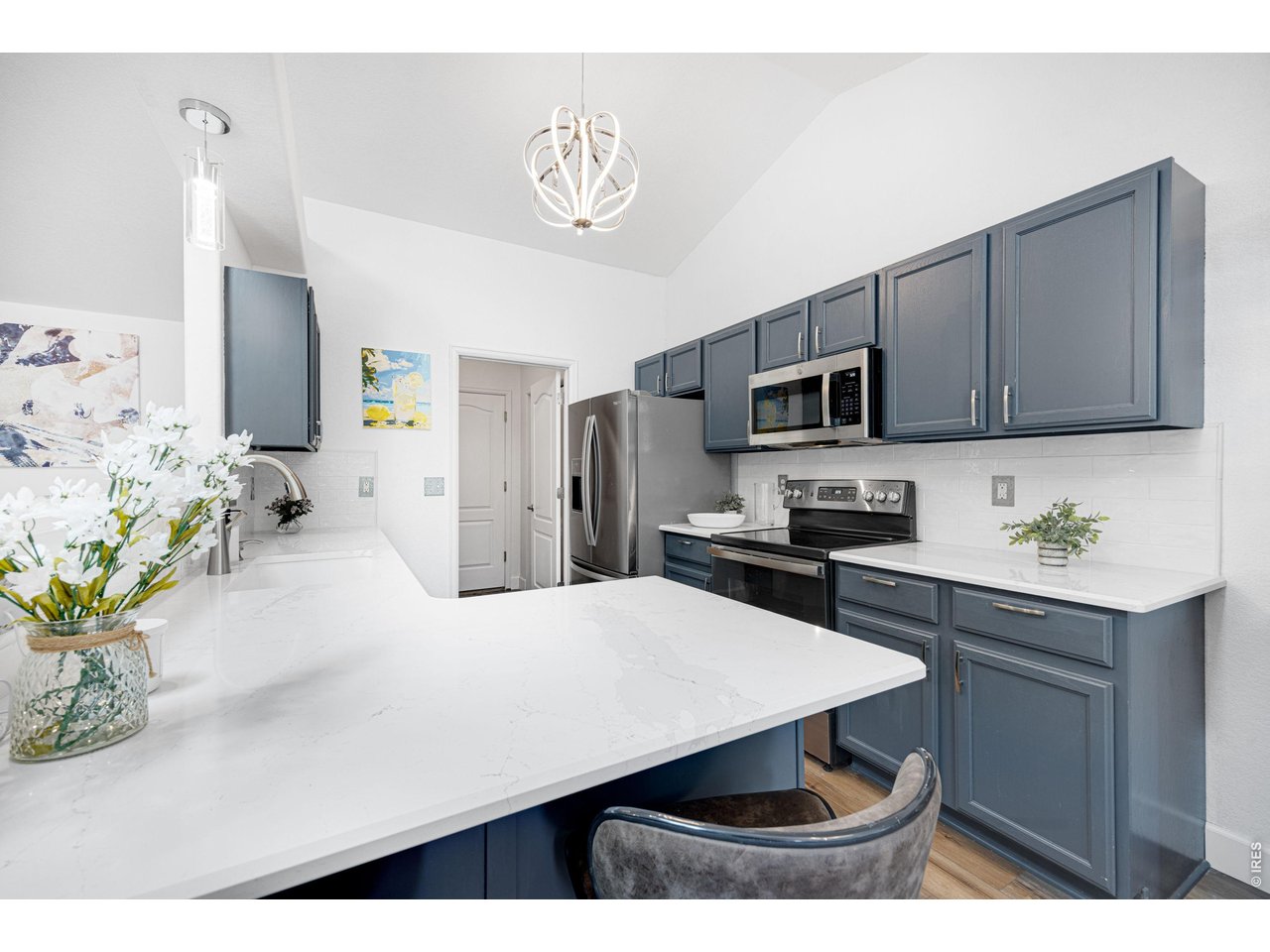 148 Beacon Way Windsor, CO 80550 - Photo 11 of 36 Updated kitchen with vaulted ceilings, granite countertops, painted cabinetry, stainless steel appliances, modern lighting, and breakfast island bar seating.