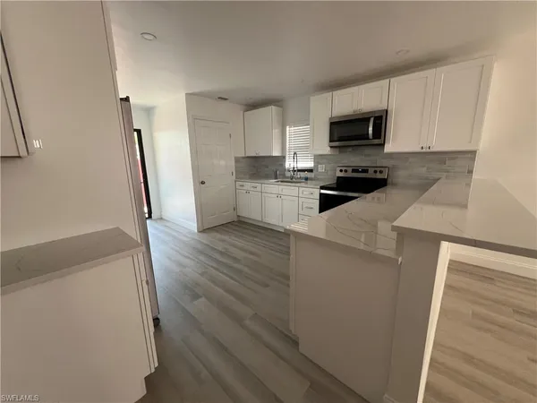 a kitchen with granite countertop a refrigerator a stove top oven a sink and dishwasher