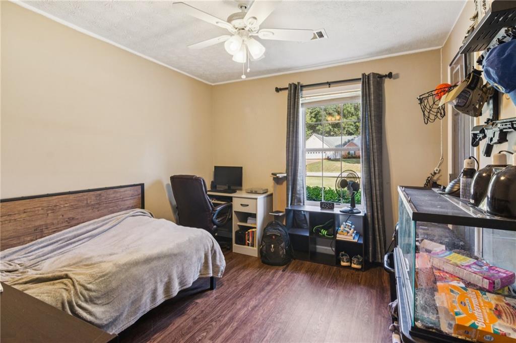 115 Alcovy Circle Covington, GA 30014 - Photo 18 of 27 a bedroom with a bed a desk and chair with wooden floor