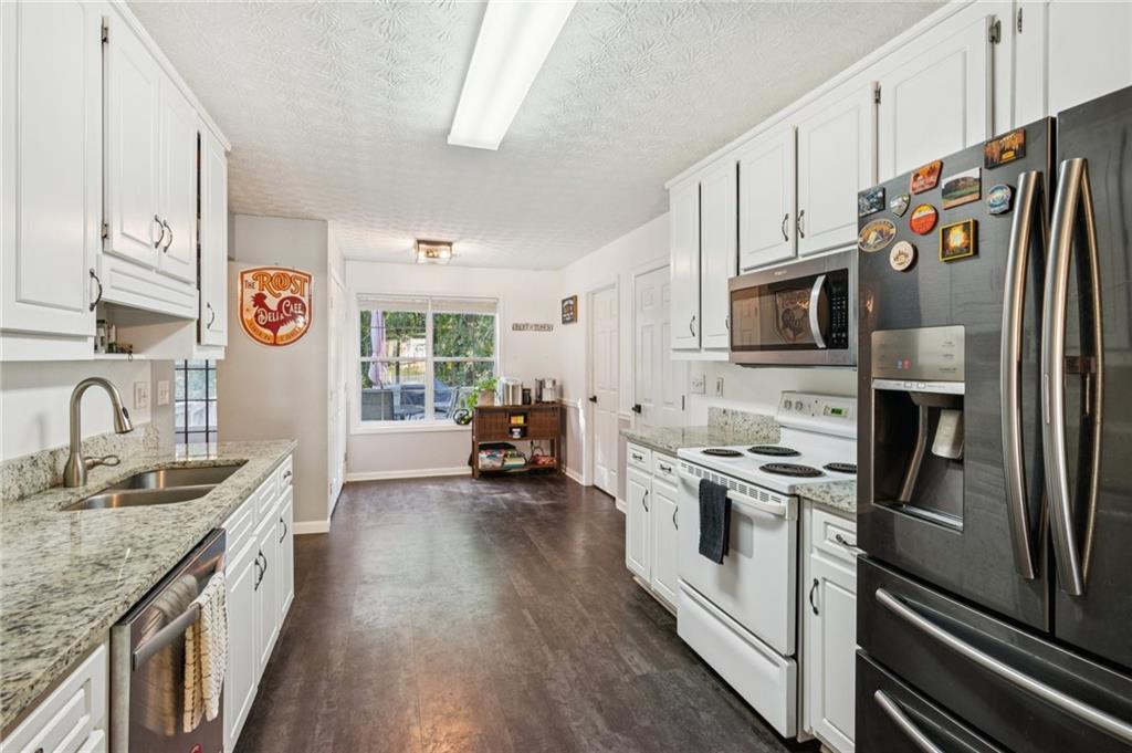 115 Alcovy Circle Covington, GA 30014 - Photo 8 of 27 a kitchen with stainless steel appliances granite countertop a refrigerator a stove and a sink with wooden floor