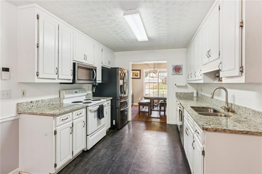 115 Alcovy Circle Covington, GA 30014 - Photo 10 of 27 a kitchen with stainless steel appliances granite countertop a stove top oven a sink dishwasher a refrigerator and a microwave oven with wooden floor