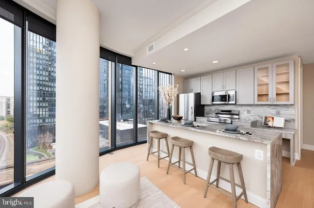 a kitchen with stainless steel appliances granite countertop a stove a sink a refrigerator a dining table and chairs