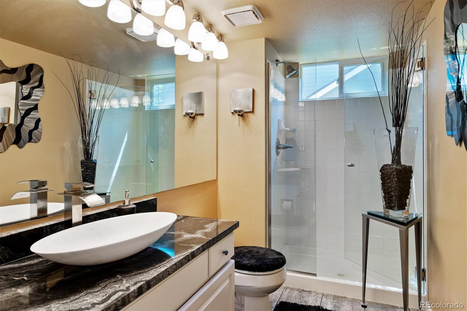 9812 South Spring Hill Place Highlands Ranch, CO 80129 - Photo 13 of 27 a bathroom with a granite countertop sink toilet a mirror and shower