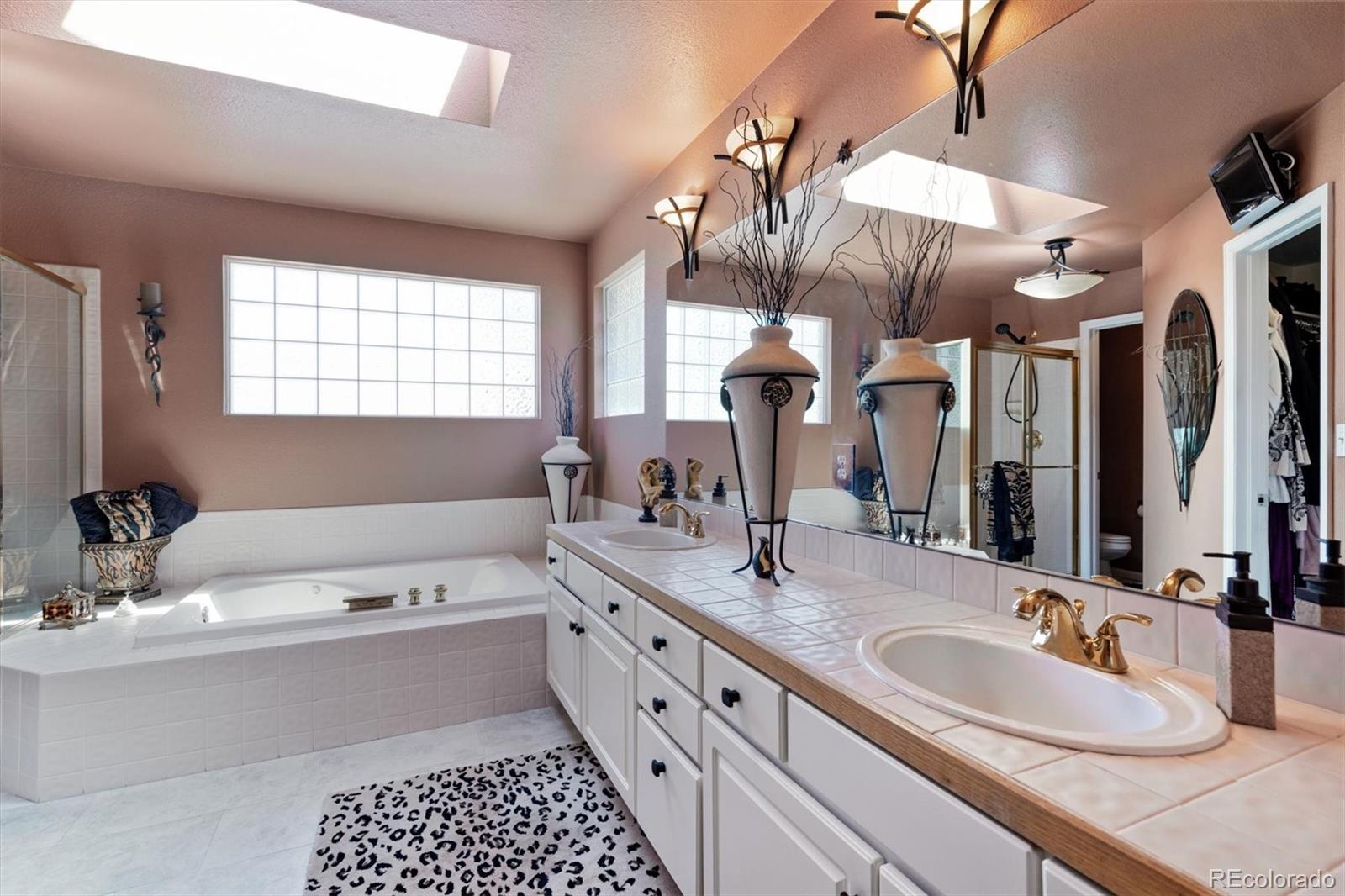 9812 South Spring Hill Place Highlands Ranch, CO 80129 - Photo 17 of 27 a bathroom with a double vanity sink a mirror and a bathtub