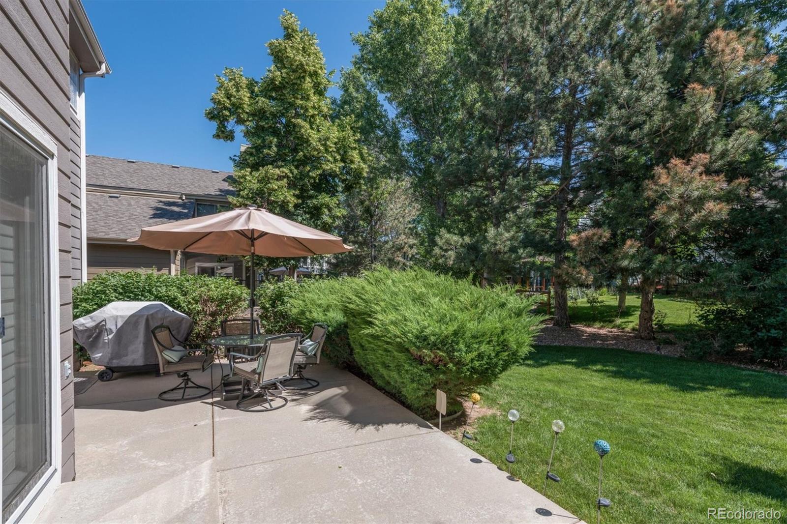 9812 South Spring Hill Place Highlands Ranch, CO 80129 - Photo 25 of 27 a backyard of a house with table and chairs under an umbrella
