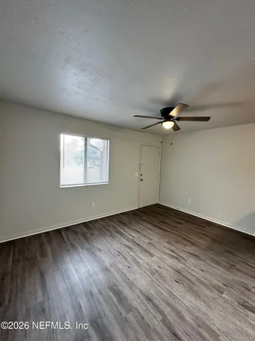 an empty room with wooden floor a ceiling fan and windows