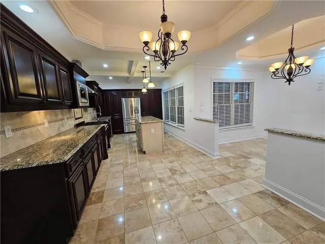 a kitchen with kitchen island granite countertop a stove a sink a counter space and cabinets