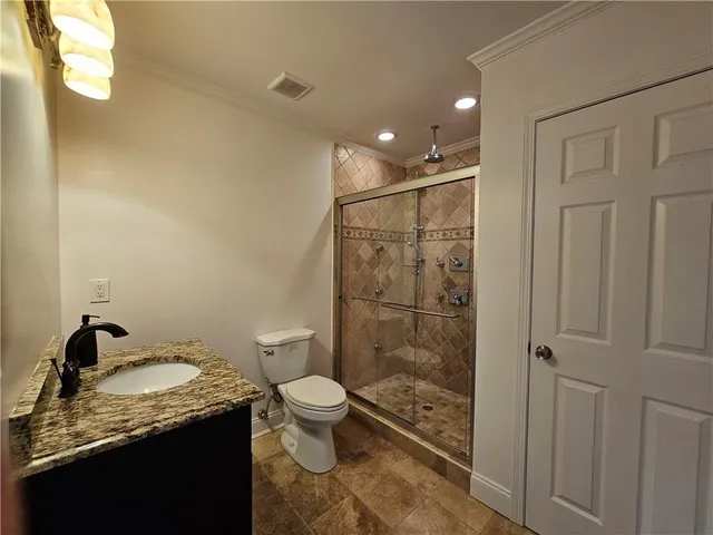 a bathroom with a granite countertop sink a toilet and shower