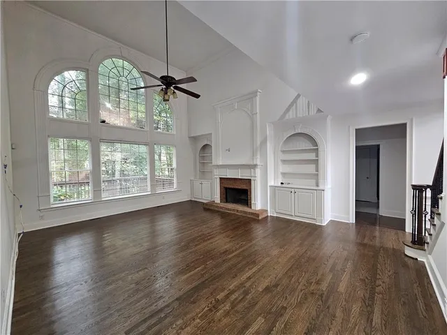 an empty room with wooden floor a fireplace and windows